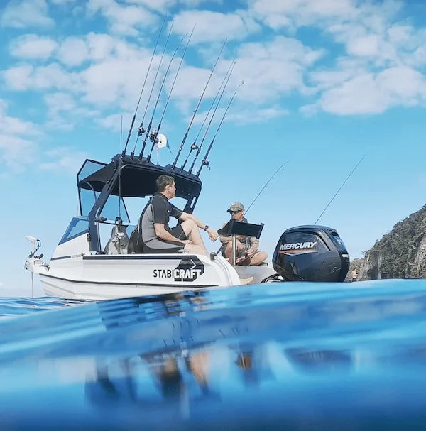 Mike Edgington & friend on a fishing boat on the water with people and scenic background